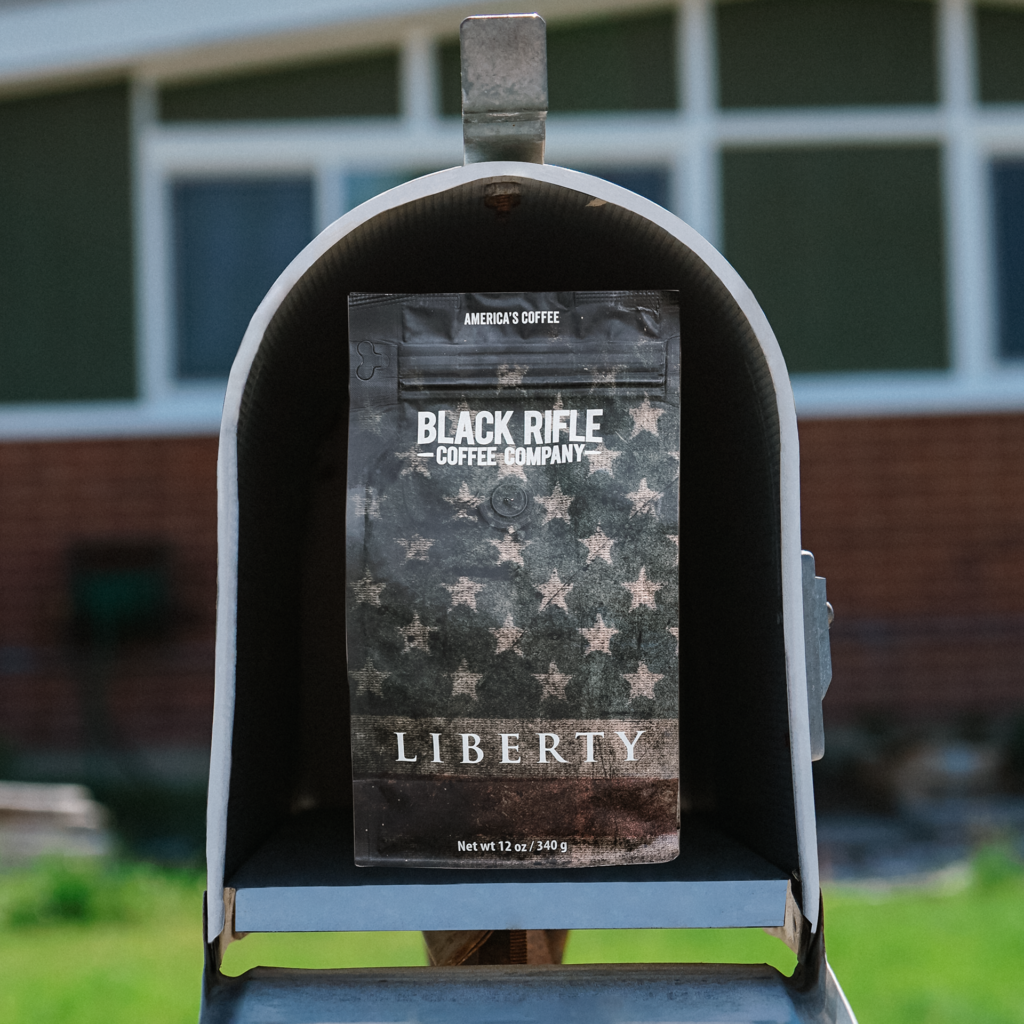 Black Rifle Coffee Company bag of coffee in a mailbox in front of a house.